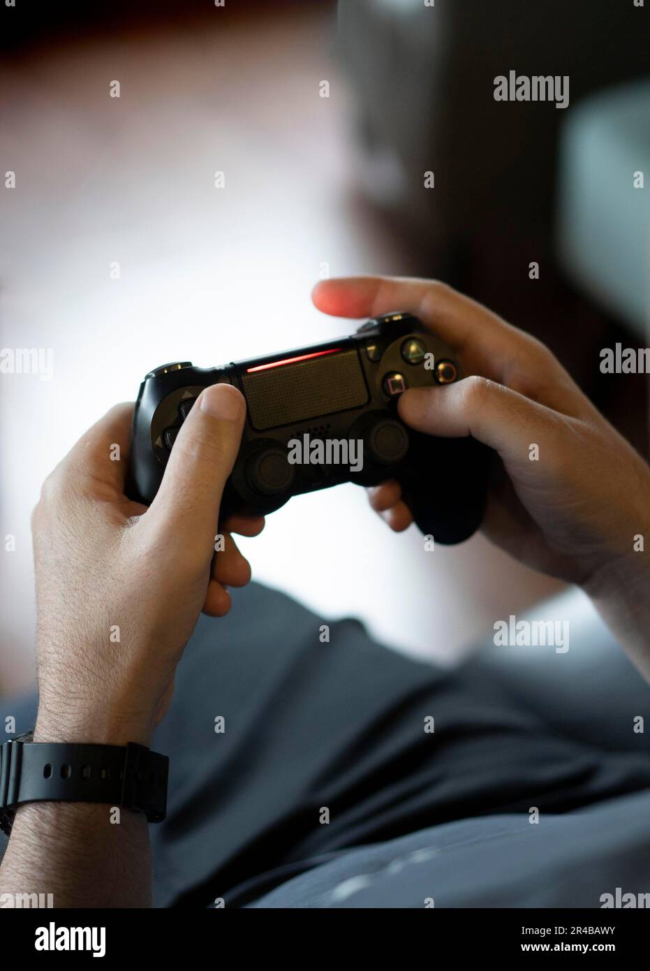 Blick aus dem großen Winkel auf die Hände eines erwachsenen Mannes, der einen Joystick hält, während er ein Videospiel auf einer Konsole spielt Stockfoto