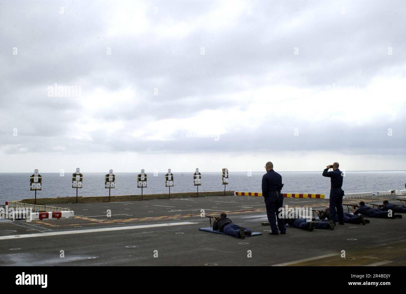 US Navy zwei Kameraden von Schützen überwachen mehrere Matrosen, die an einer M-14-Gewehrqualifizierung auf dem Flugdeck des Amphibienschiffes USS Peleliu (LHA 5) teilnehmen. Stockfoto