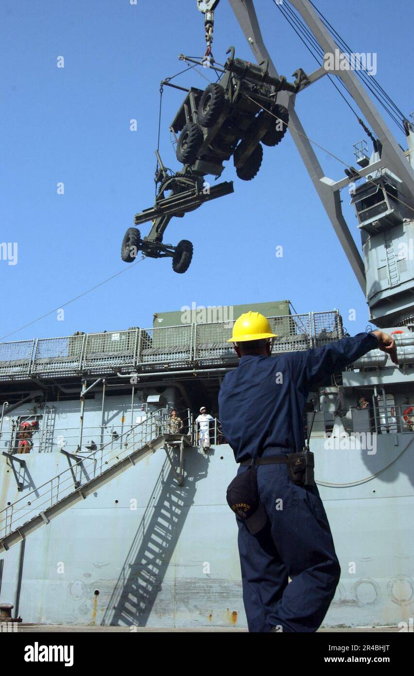 US Navy USA Navy Boatswain's Mate 2. Class leitet einen Kran, der ein schweres Gerät trägt, während er Vorräte vom Cockpit des Dock-Landungsschiffes USS Pearl Harbor (LS. Stockfoto