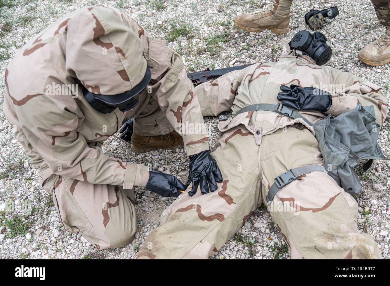 Ein Soldat mit Mission Oriented Protective Hold (MOPP)-Ausrüstung bereitet sich auf den Test des Advanced Antiepilepsant System Rafa Midazolam Auto-Injector (Rafa AI) an einem anderen Soldat in Camp Bullis, Texas, vor. Der Test wurde von den USA organisiert Army Medical Center of Excellence Medizinische Test- und Evaluierungsaktivität zur Durchführung einer menschlichen Einflussnahme auf die Wirksamkeit der Rafa KI und ob das Gerät die Standards des Joint Program Executive Office - Chemische, biologische, radiologische, nukleare Verteidigung erfüllt. Stockfoto
