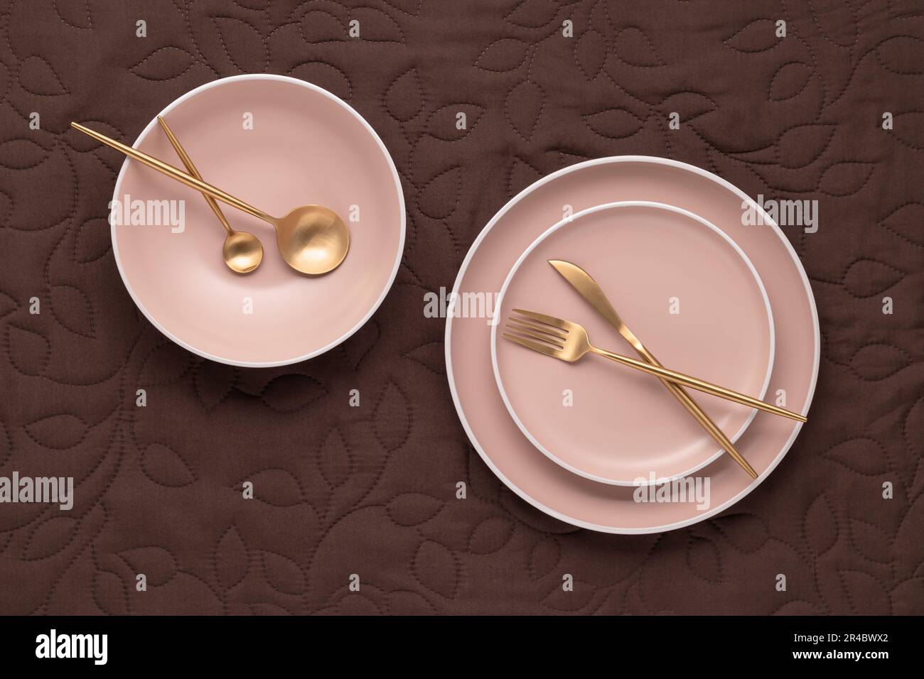Ein Satz runder beigefarbener Platten in verschiedenen Größen auf dem Tisch, Draufsicht. Goldenes Besteck und Servierutensilien. Modernes, trendiges Keramikgeschirr. Eine leere PL Stockfoto