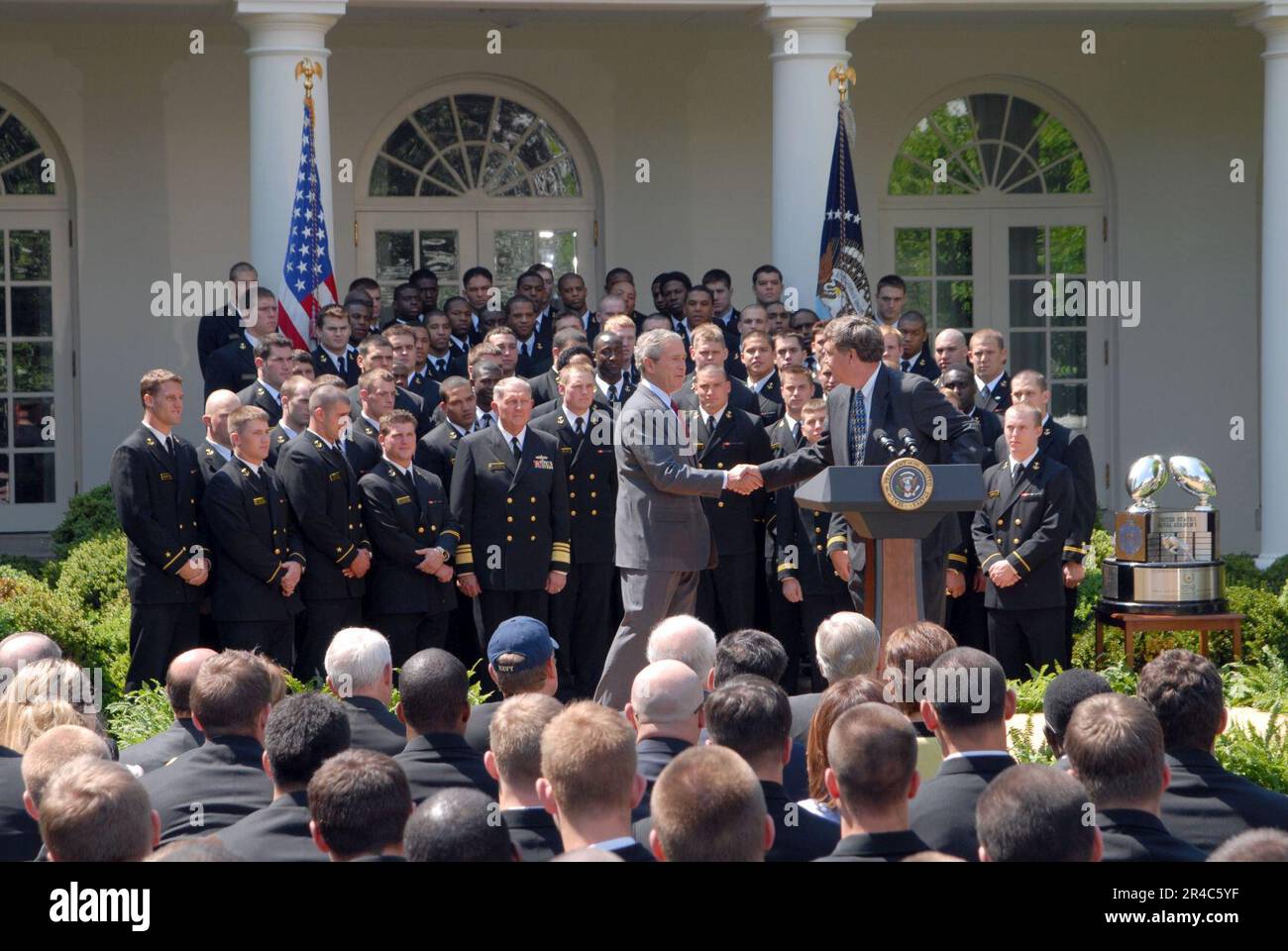US Navy President George W. Bush schüttelt dem Navy Football Coach Paul Johnson die Hand, während er die Trophäe des Oberbefehlshabers dem US Naval Academy Football Team im White Ho präsentiert. Stockfoto