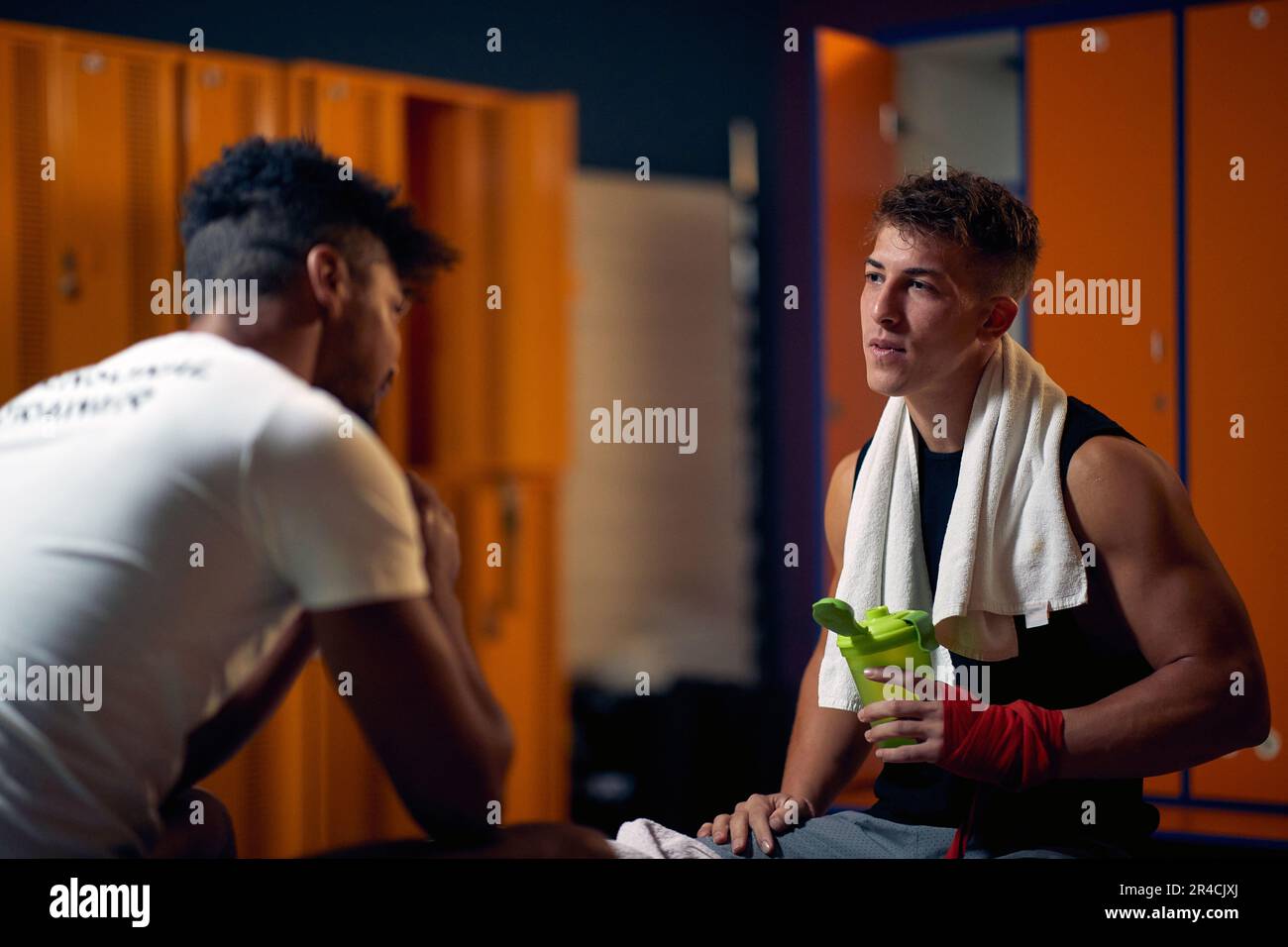 Junger Boxer in der Garderobe, sitzt mit dem Trainer und redet. Personal Trainer ermutigt jungen Spieler. Sport, Kampfsport, Lifestyle-Konzept. Stockfoto