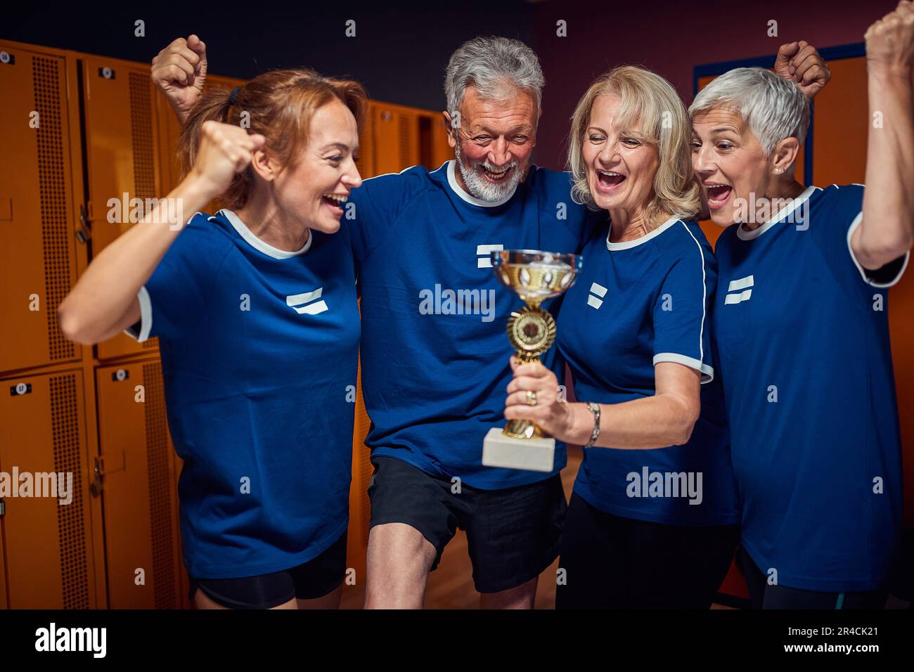 Team von Senior-Fußballspielern, die den Sieg feiern, den goldenen Pokal halten und sich gemeinsam im Umkleideraum siegen fühlen. Sport, Seniorenleben, aktives Leben Stockfoto