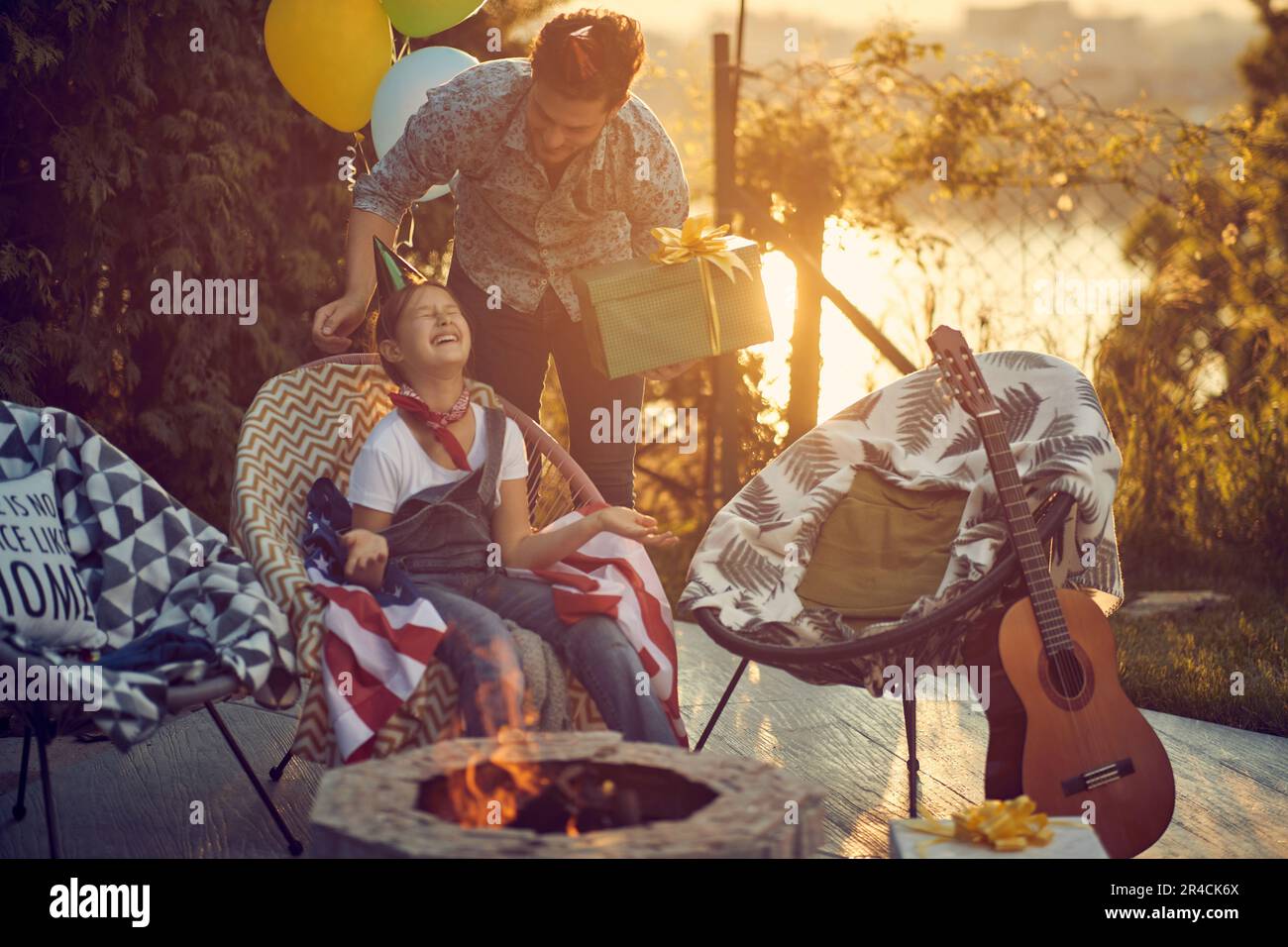 Ein besonderer Moment zwischen einem Vater und seiner Tochter an ihrem Geburtstag. Das Bild zeigt den Vater, der seiner Tochter ein Geschenk überreicht, mit dem Aussehen eines Stockfoto