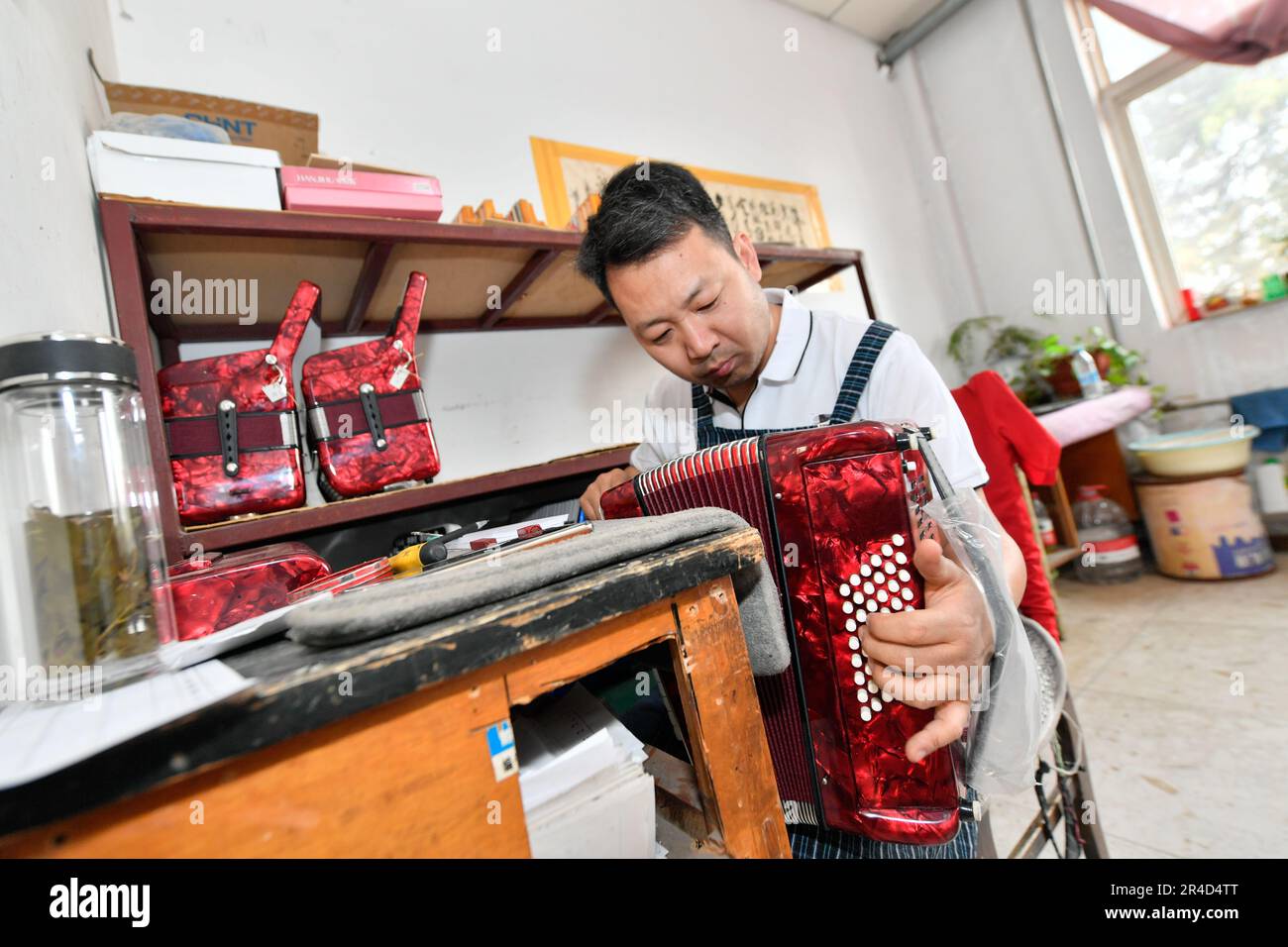 (230527) -- TIANJIN, 27. Mai 2023 (Xinhua) -- Ein Arbeiter spielt ein Akkordeon bei Tianjin Yingwu Musical Instrument Co., Ltd. In Zhongwang, Stadt Jinghai, Nordchina Tianjin, 25. Mai 2023. Tianjin Yingwu Musical Instrument Co., Ltd. Ist ein Unternehmen mit einer 71-jährigen Geschichte in der Akkordeonherstellung. In den 1950er Jahren produzierte seine Vorgängerin Tianjin Musical Instrument Factory das erste Akkordeon im neuen China mit der Marke „Yingwu“. Von da an wurden die hier hergestellten Yingwu-Akkordeons zu Hause und im Ausland berühmt. In den letzten Jahren hat das Unternehmen technische Arbeiten durchgeführt Stockfoto