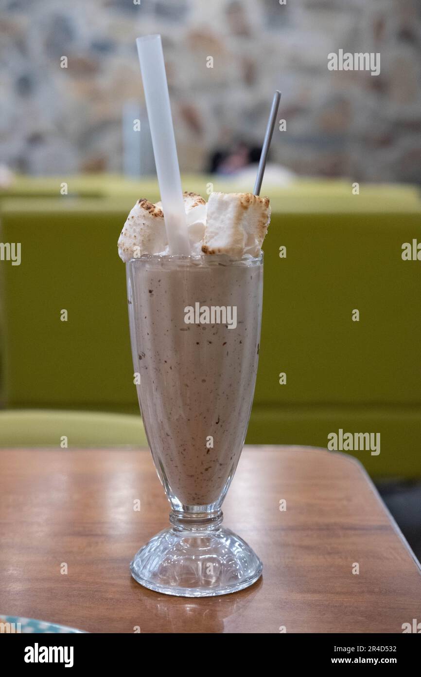 Schokoladenmilch Shake mit verbranntem Marshmallow auf dem Tisch, mit verschwommenem Hintergrund Stockfoto