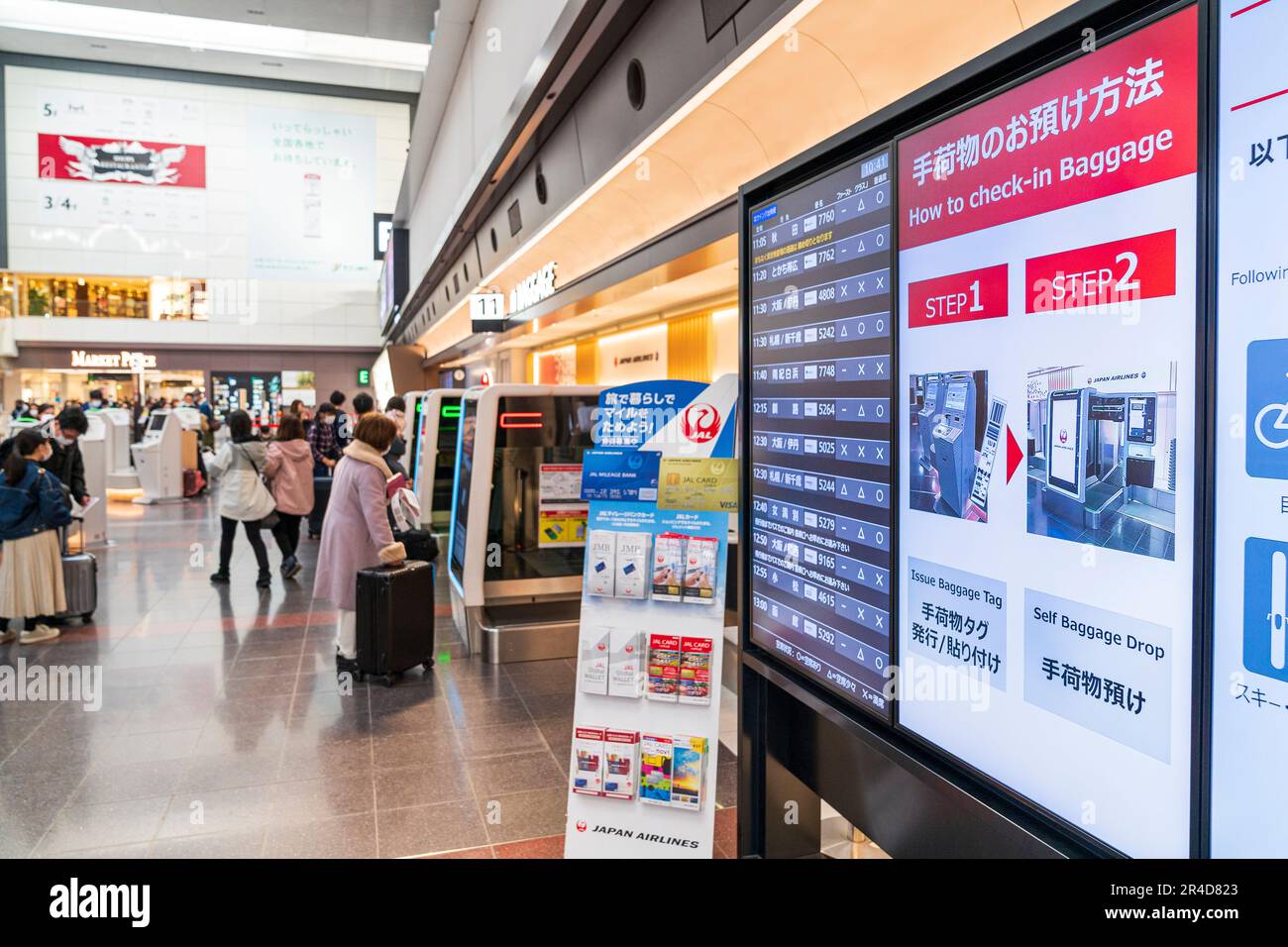 Videoanzeige an der Wand zur Gepäckabfertigung und Informationen zum Abflug, Hintergrund, Unscharfstellung Personen, die Gepäck aufgeben. Flughafen Haneda. Stockfoto
