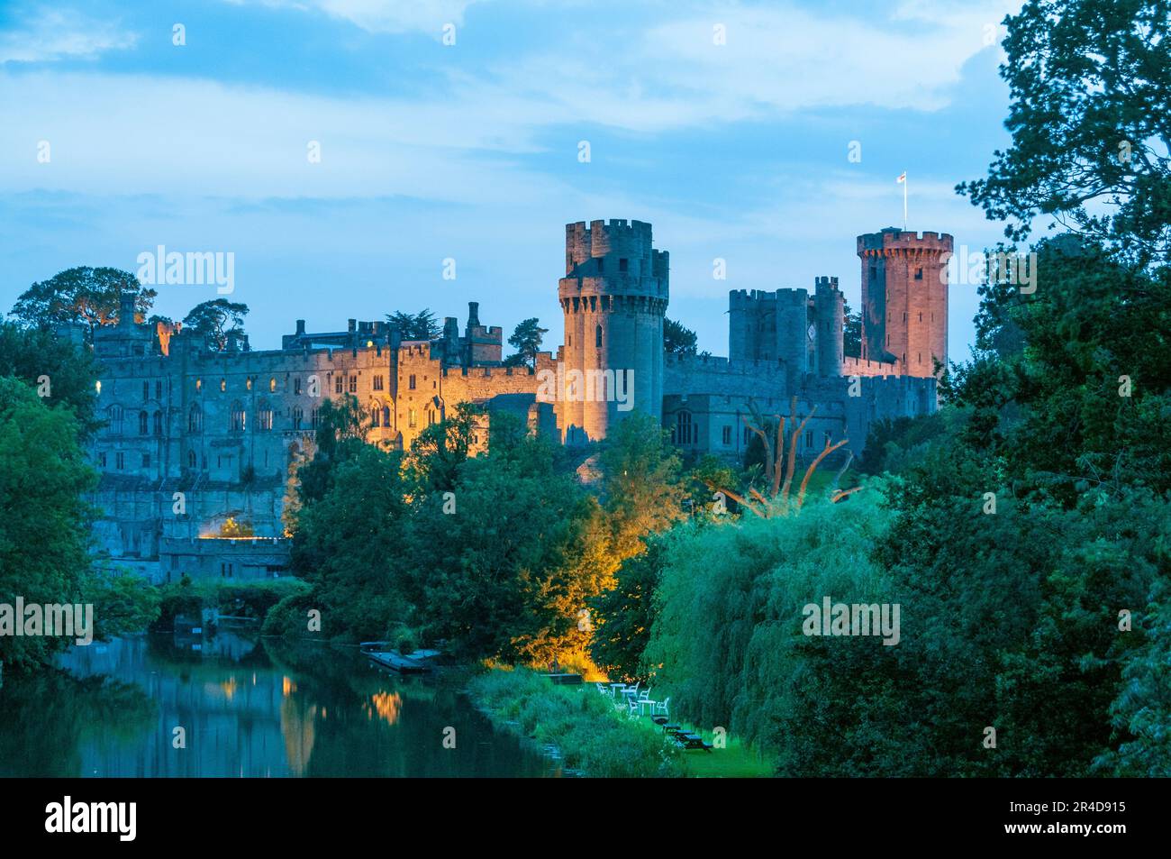 Das aus dem 12. Jahrhundert erbaute Warwick Castle, reich an englischer Geschichte, liegt am Ufer des Flusses Avon und ist in der Dämmerung der Geschichte mit Lichtern getaucht Stockfoto