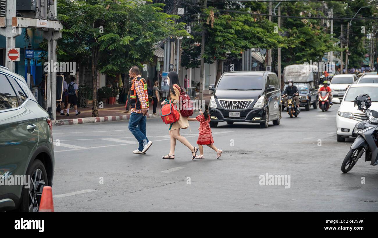 Menschen, die die Chak Phet Straße zur morgendlichen Verkehrszeit auf dem Bangkok Flower Market (Pak Khlong Talat) überqueren, der sich am Fluss Chao Phraya auf der Insel Rattanakosin im Viertel Phra Nakhon befindet. Bangkok Flower Market (Pak Khlong Talad) Thailands größter Blumengroßmarkt, 24 Stunden am Tag, 7 Tage die Woche geöffnet, neben einem Markt für frisches Gemüse, Obst und Kräuter, an der Chak Phet Road, in der Nähe der Gedächtnisbrücke (Saphan Phut) in der historischen Altstadt. Stockfoto