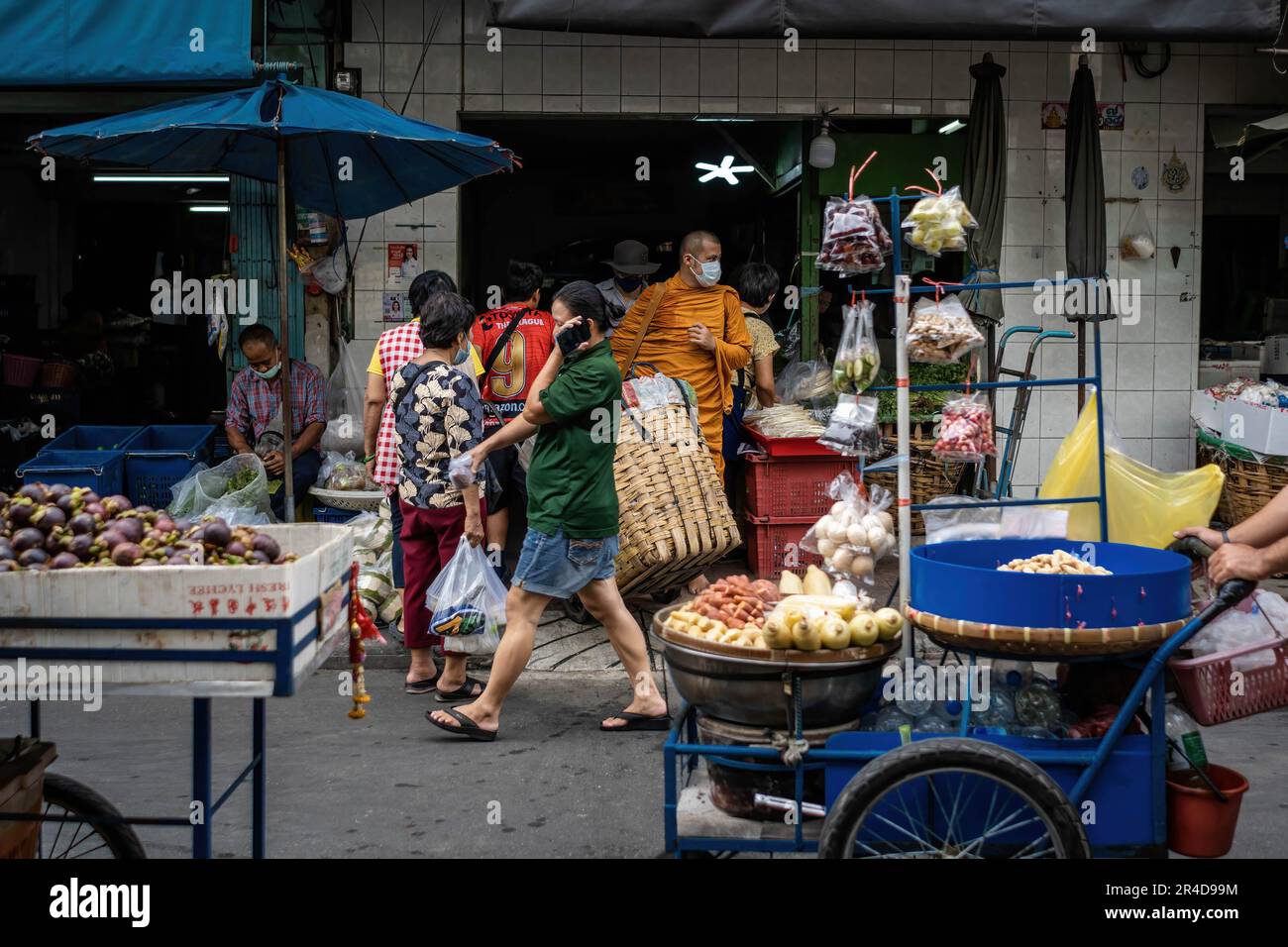 Passanten und Straßenverkäufer sind an einem der Eingänge des Bangkok Flower Market (Pak Khlong Talat) zu sehen. Bangkok Flower Market (Pak Khlong Talad) Thailands größter Blumengroßmarkt, 24 Stunden am Tag, 7 Tage die Woche geöffnet, neben einem Markt für frisches Gemüse, Obst und Kräuter, an der Chak Phet Road, in der Nähe der Gedächtnisbrücke (Saphan Phut) in der historischen Altstadt. Stockfoto