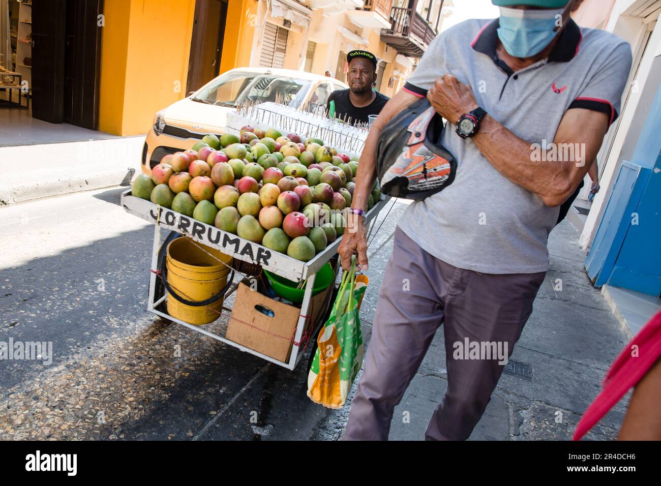 Ein Mann schiebt einen Wagen voller Papayas dow auf die Straße in Cartagena Kolumbien Stockfoto