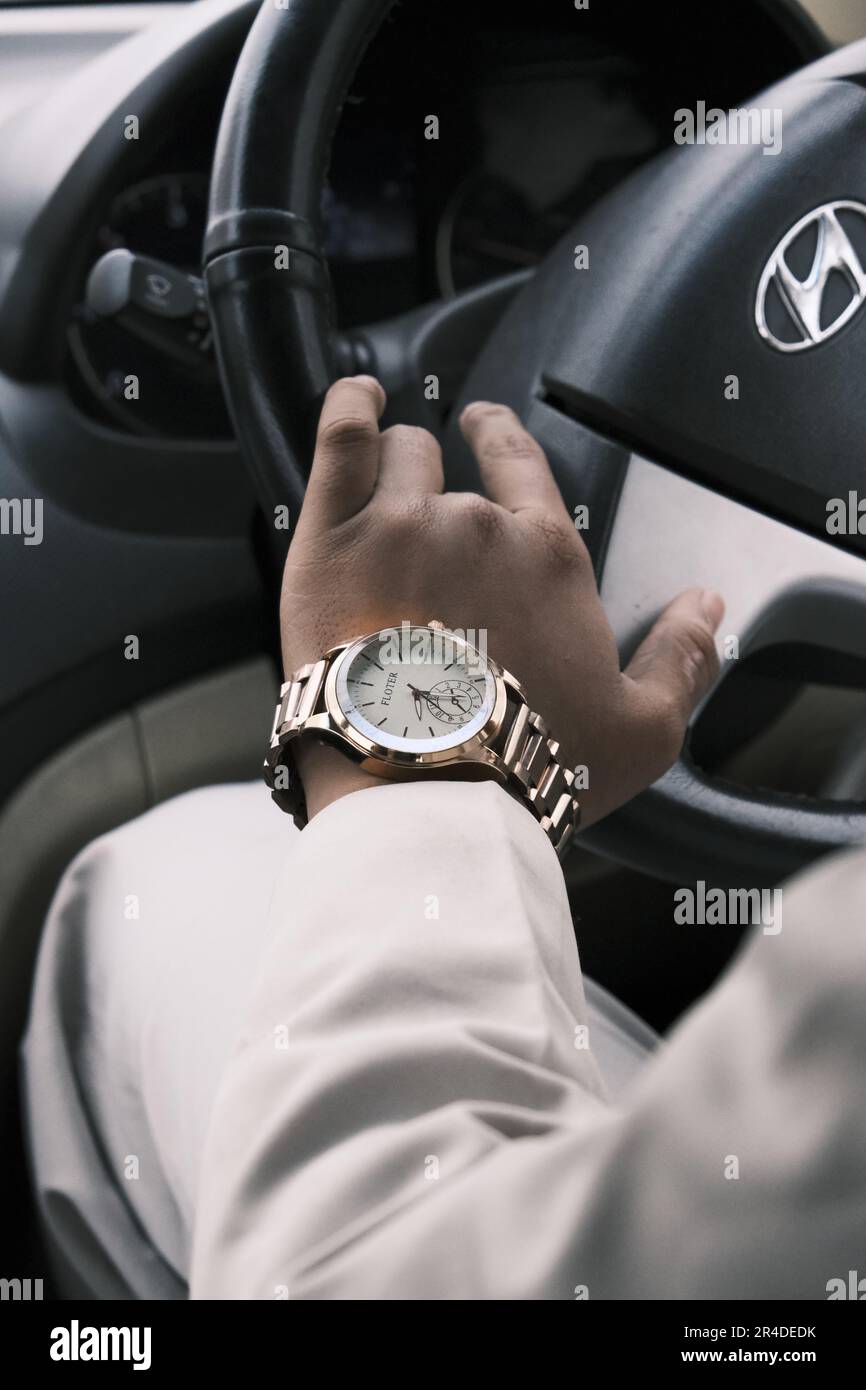 Ein erwachsener Mann, der ein Auto fährt und dabei eine goldene Armbanduhr trägt, unterstreicht seinen Erfolg und seinen hohen Status Stockfoto
