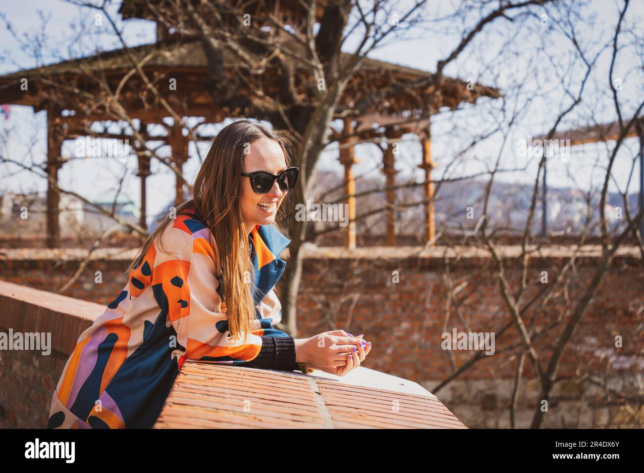 Junge Frau mit Sonnenbrille in einer bunten Jacke in Budapest Stockfoto