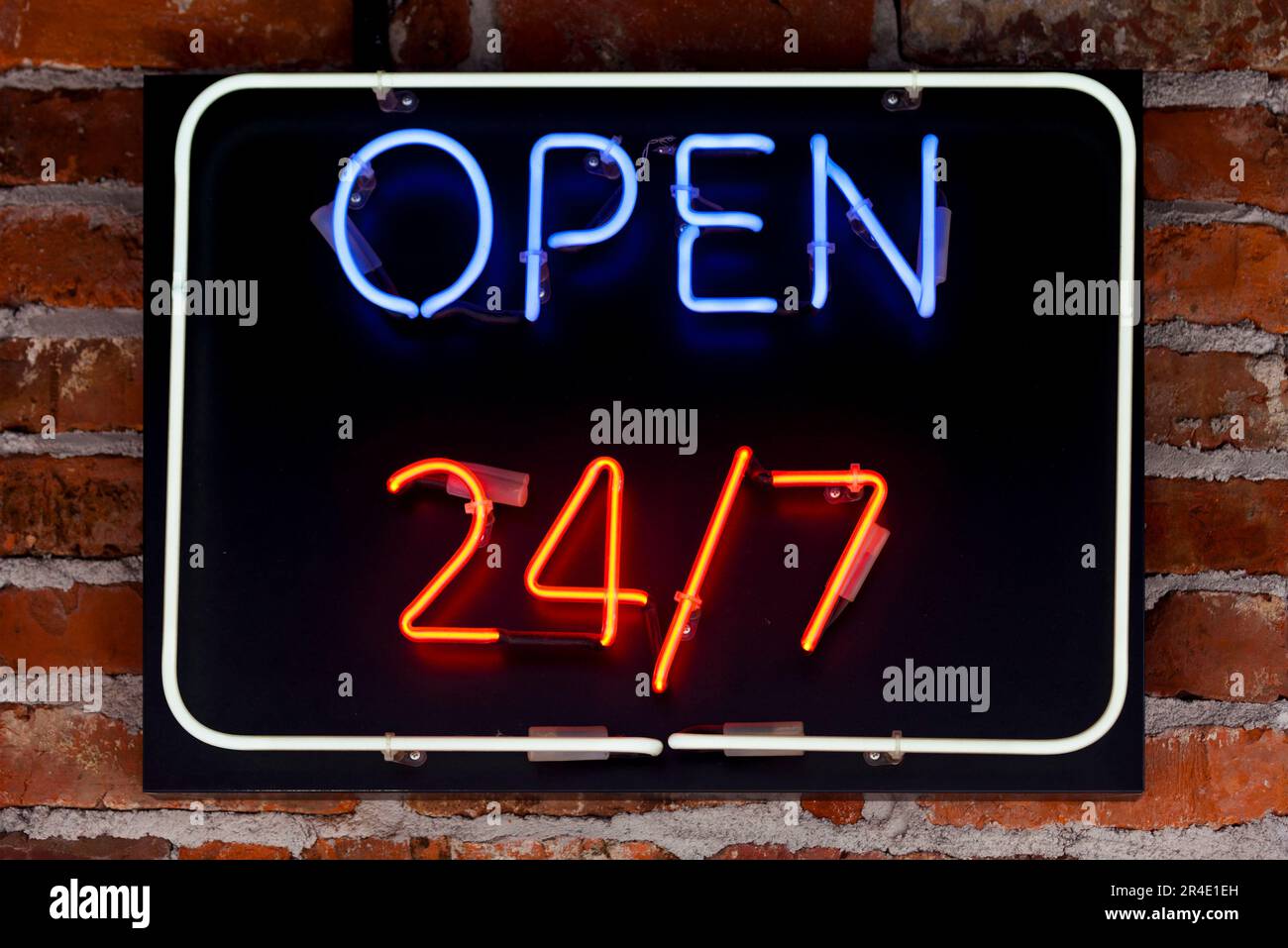 Nahaufnahme eines Neonlichts in Form eines kurzen Satzes „24/7 öffnen“. Stockfoto