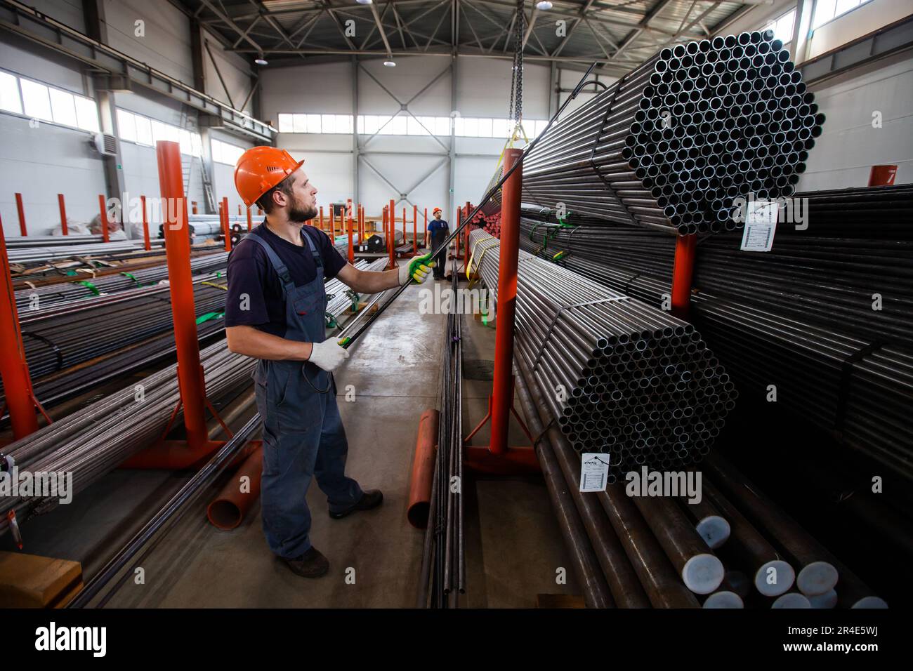 Podolsk, Provinz Moskau - 02. August 2021: Rohrlager. Arbeiter bewegen Rohre mit Haken und Deckenkran. Stockfoto