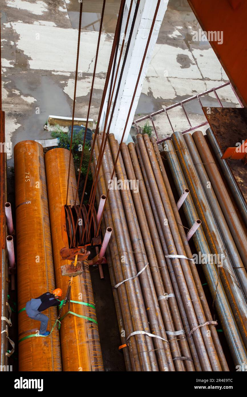 Arbeiter befestigte verrostete Rohre mit Gurten am Kranhaken Stockfoto