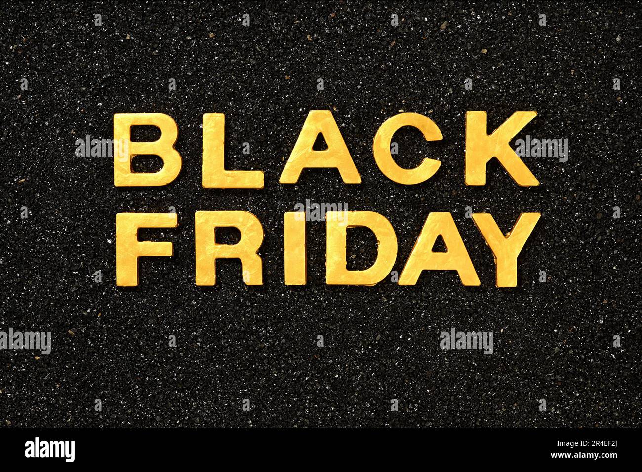 Black Friday – Text mit goldenen Buchstaben im schwarzen Sand Stockfoto
