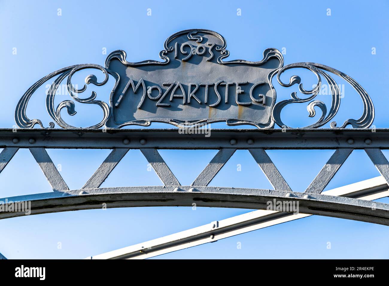 Die Inschrift „Mozartsteg 1903“ ziert die Jugendstil-Fußgängerbrücke im Zentrum von Salzburg, Österreich. Der Mozartstegverein finanzierte die Brücke privat. Bis 1921 wurde eine Maut erhoben. Dann kaufte die Stadt Salzburg die Brücke und öffnete sie für Fußgänger und Radfahrer. Stockfoto