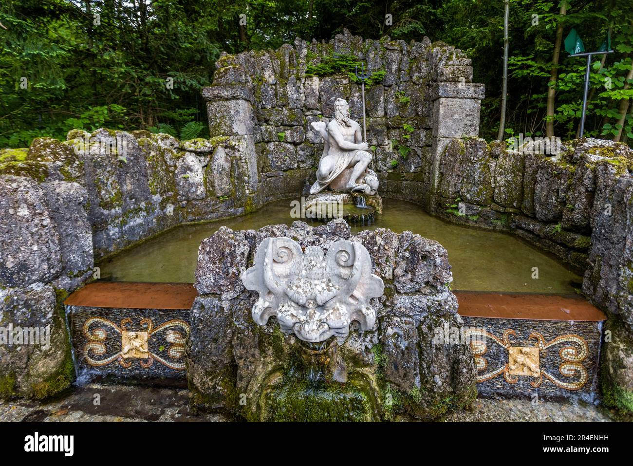 Neptun-Brunnen, eine Statue des gottes Neptun, der auf einem Delfin im Schloss Hellbrunn in Salzburg, Österreich sitzt. Vor dem Stein befindet sich eine groteske Marmormaske, aus deren Mund Wasser fließt Stockfoto