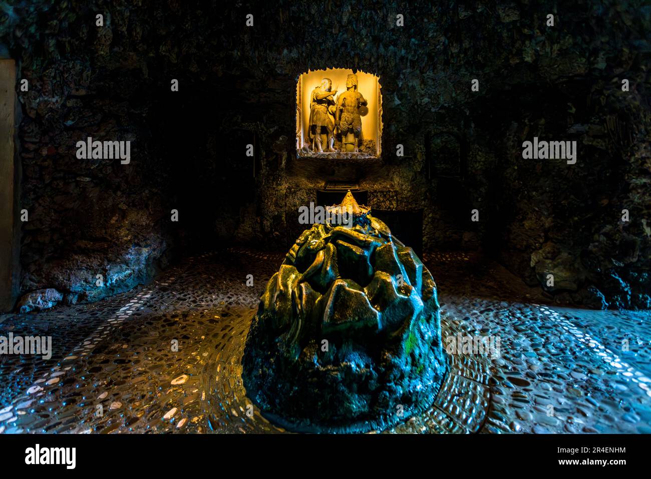 Eine goldene Krone schwebt auf einem Wasserstrahl über einem felsartigen Hügel in der Mydas- oder Kronenhöhle der Trickfontänen im Schloss Hellbrunn in Salzburg, Österreich. In einer beleuchteten Nische dahinter steht eine Marmorgruppe aus zwei männlichen Figuren, die den Gott Apollo und Marsyas darstellen sollen, den er bestraft hat. Die Grotte ist nach dem legendären König Midas benannt, dem in der griechischen Mythologie Esels Ohren als Strafe für sein Urteil gegen Apollo verliehen wurden. Fürsterzbischof Markus Sitticus von Hohenems ließ den Lustschloss als Sommerresidenz in den Jahren 1613–1619 errichten. Stockfoto