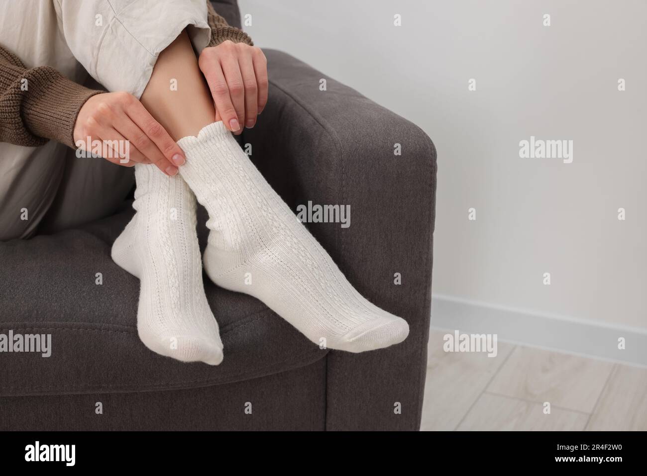 Eine Frau in warmen Socken, die sich zu Hause auf dem Sessel entspannt. Platz für Text Stockfoto