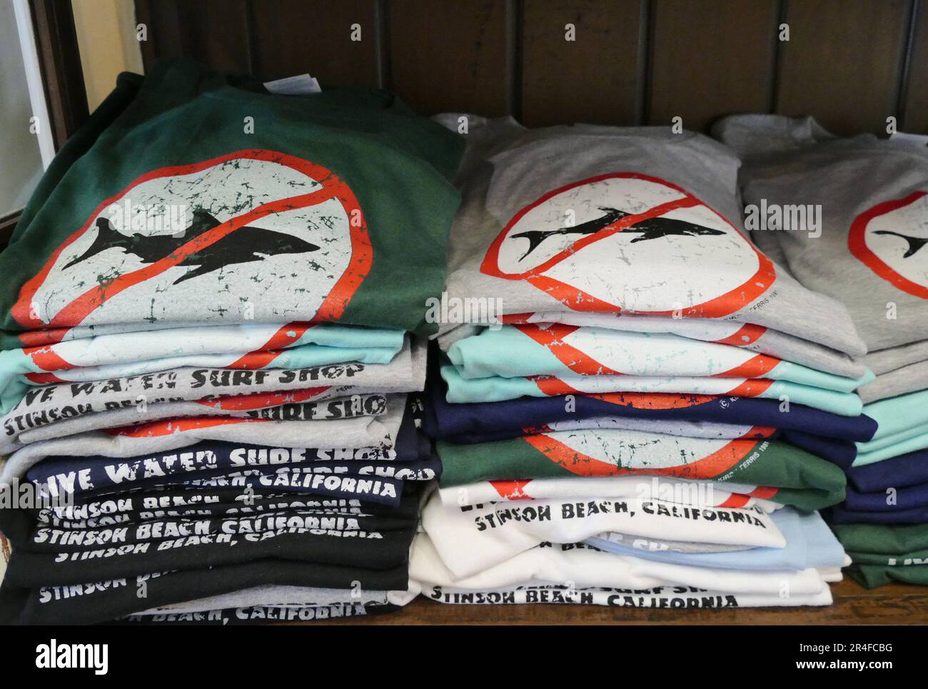 Stinson Beach, USA. 13. Mai 2023. Das legendäre „No Shark“-Logo ist auf T-Shirts zu sehen, die in einem Surfgeschäft an der kalifornischen Küste zum Verkauf angeboten werden. Haie faszinieren Menschen auf der ganzen Welt. (Zu dpa-KORR Urlaub unter Haien: Ein Ausflug in die Hotspots der Meeresjäger) Kredit: Barbara Munker/dpa/Alamy Live News Stockfoto