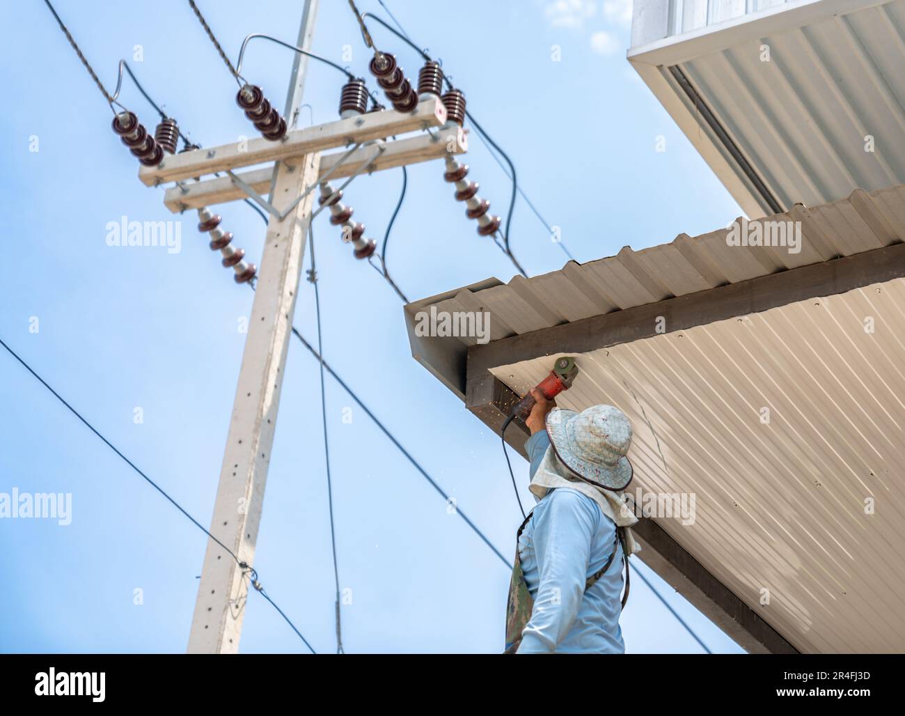 Die Arbeiter verwenden Chiasteine, um Metallblechdecken auf der Baustelle zu schneiden. Stockfoto