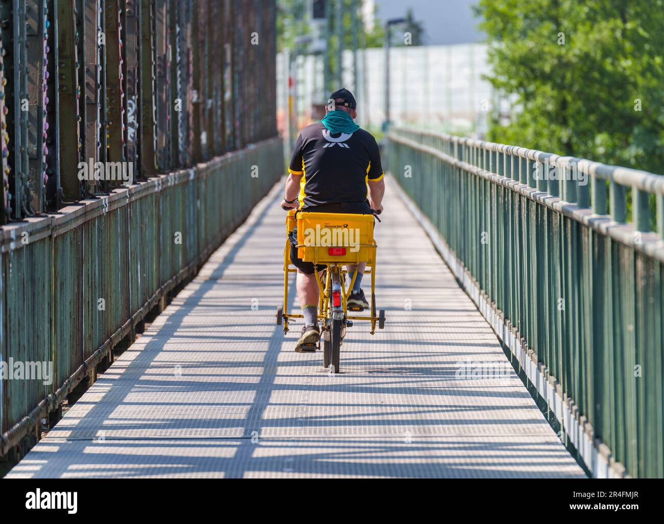 27. Mai 2023, Hessen, Frankfurt/Main: Ein Briefträger fährt sein Fahrrad über eine Brücke ohne Elektroantrieb. Foto: Andreas Arnold/dpa Stockfoto