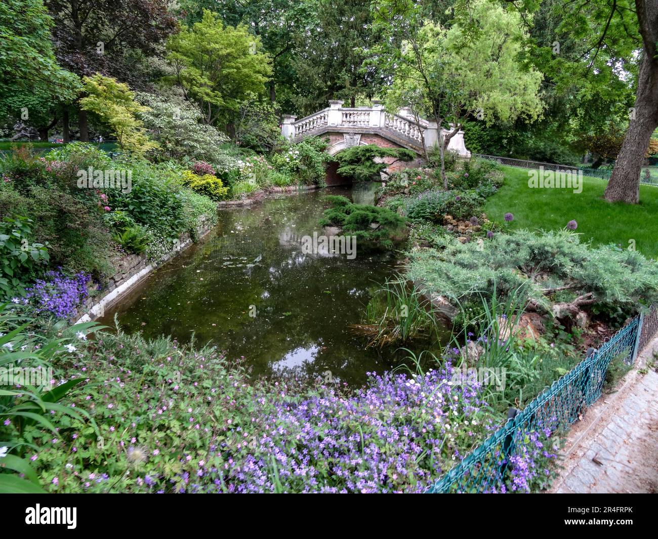 Intimes, hochauflösendes urbanes Landschaftsbild einer romantischen Brücke über den Fluss im Parque Monceau, Paris, Frankreich Stockfoto