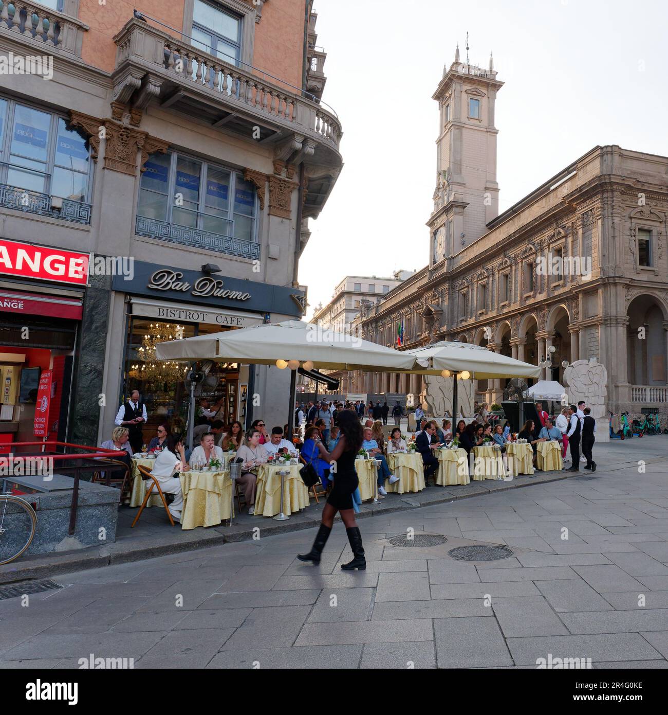 Lady in Black spaziert vorbei an der Bar Duomo gegenüber dem Palazzo dei Giureconsulti in der Stadt Mailand, Lombardei, Italien Stockfoto