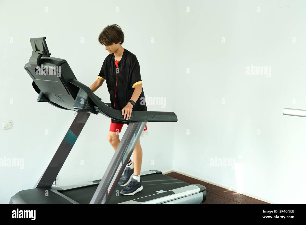 Ein Teenager, der im Fitnessstudio auf dem Laufband läuft. Sport, Kardio, Krafttraining, Fitnesskonzept. Stockfoto
