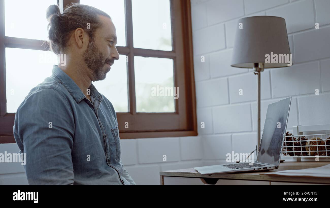 Ein junger besorgter Mann, der auf dem Schreibtisch saß und ein Notebook benutzte. Stockfoto