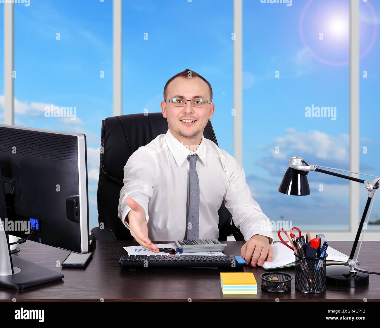 Ein Geschäftsmann, der im Amt sitzt und seine Hand ausstreckt Stockfoto