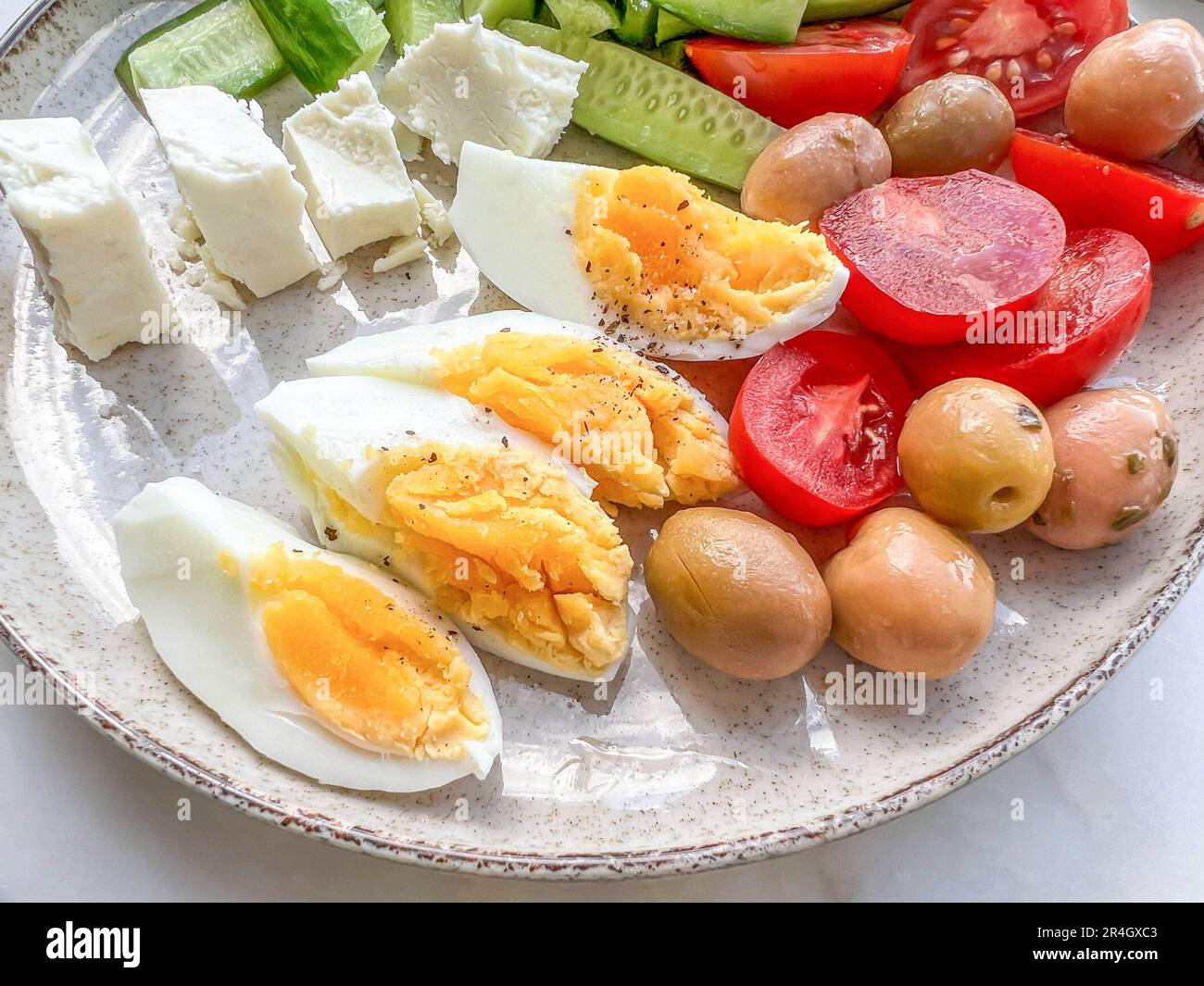 Frühstück, gesunder Frühstücksteller mit Scheiben gekochtem Ei, Käse und frischem Salat auf einem Teller mit selektivem Fokus. Konzept für gesunde und köstliche Speisen Stockfotografie