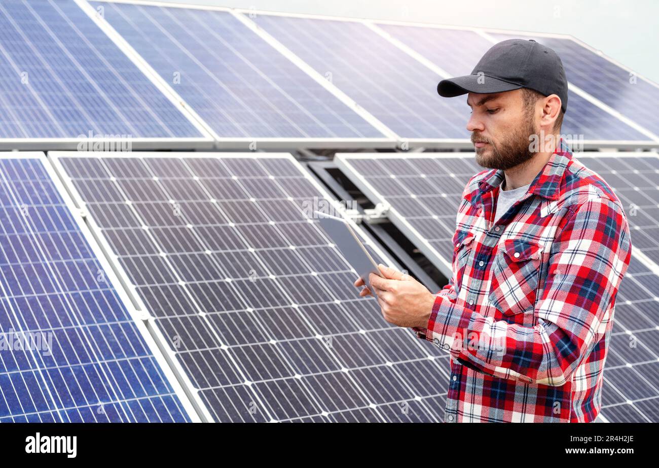 Funktion: Technischer Außendienstleiter, der ein digitales Tablet zur Leistungsbewertung von Solarpaneelen auf einer Solarenergiefarm verwendet. Stockfoto
