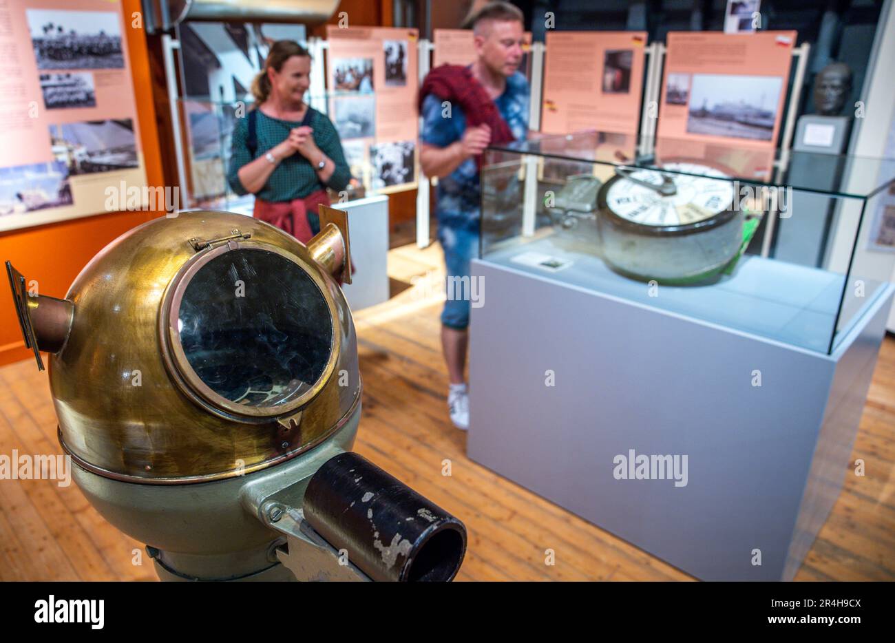 Rostock, Deutschland. 28. Mai 2023. Besucher stehen hinter dem ursprünglichen Kompassstand des Fracht- und Passagierschiffs „Georg Büchner“, das vor zehn Jahren in der Ostsee sank, in den Räumen des Museumsschiffs „Dresden“. Ein Dokumentarfilm über die Geschichte des ehemaligen belgischen Kolonialschiffes, das vor der Bucht von Danzig sank, wird am 28. Mai 2023 in Rostock Premiere finden. Vor zehn Jahren sank das Schiff, das über 153 Meter lang und 19,6 Meter breit war, ohne Besatzung. Kredit: Jens Büttner/dpa/Alamy Live News Stockfoto