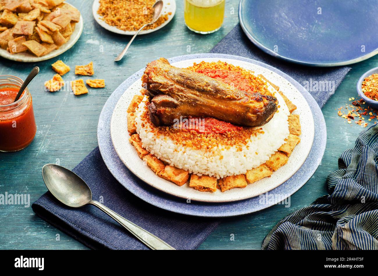 Arabische Küche; ägyptische orientalische Fattah mit weißem Reis und knusprigem Brot garniert mit gewürzter roter Knoblauchsauce, knusprigem gebratenem Knoblauch und Rindfleisch. Stockfoto