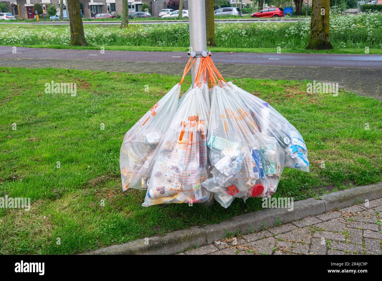 Abfallsäcke mit Verpackungsmaterial hängen an einem Lampenpfahl, um gesammelt und recycelt zu werden. Stockfoto