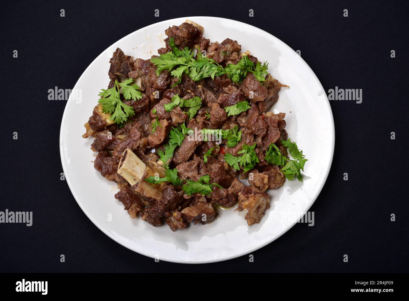 Rinderbraten mit Korianderblättern auf schwarzem Hintergrund Stockfoto