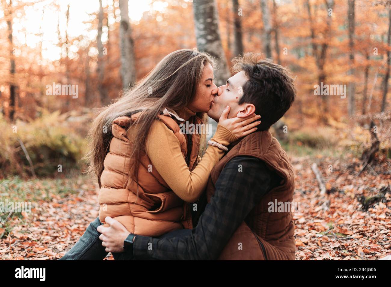 Ein junges Paar, das viel Spaß im Wald hat, sich küsst Stockfoto