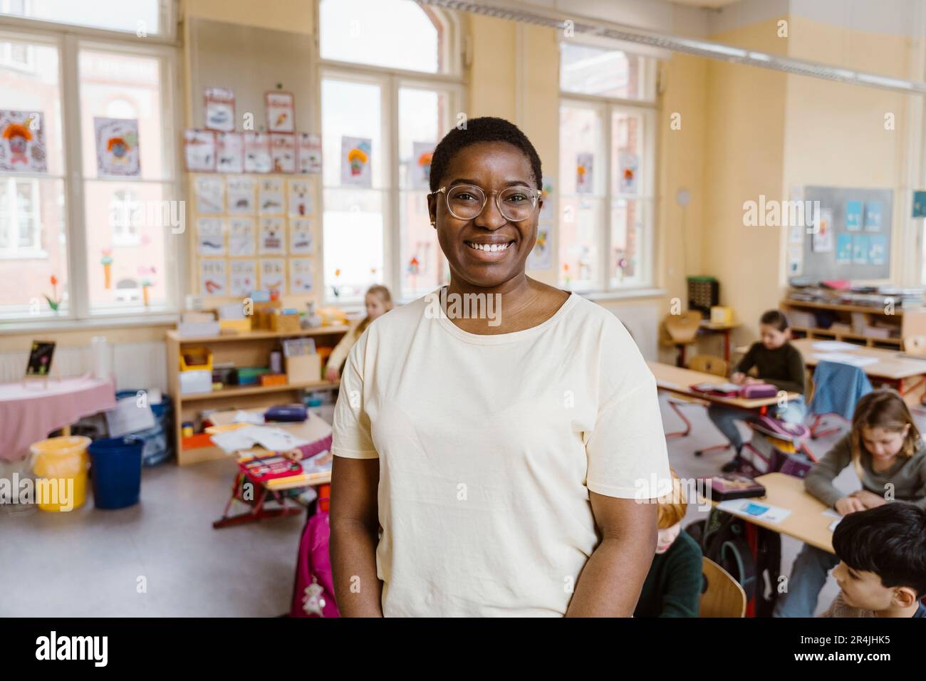 Porträt eines lächelnden Lehrers, der vor Schülern im Klassenzimmer steht Stockfoto