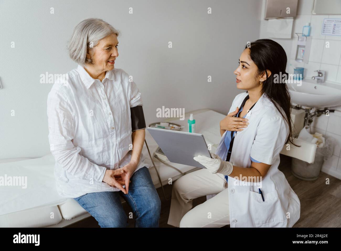 Ärztin mit Tablet-PC als Ratgeberin für leitende Patientin im Bett in der Klinik Stockfoto