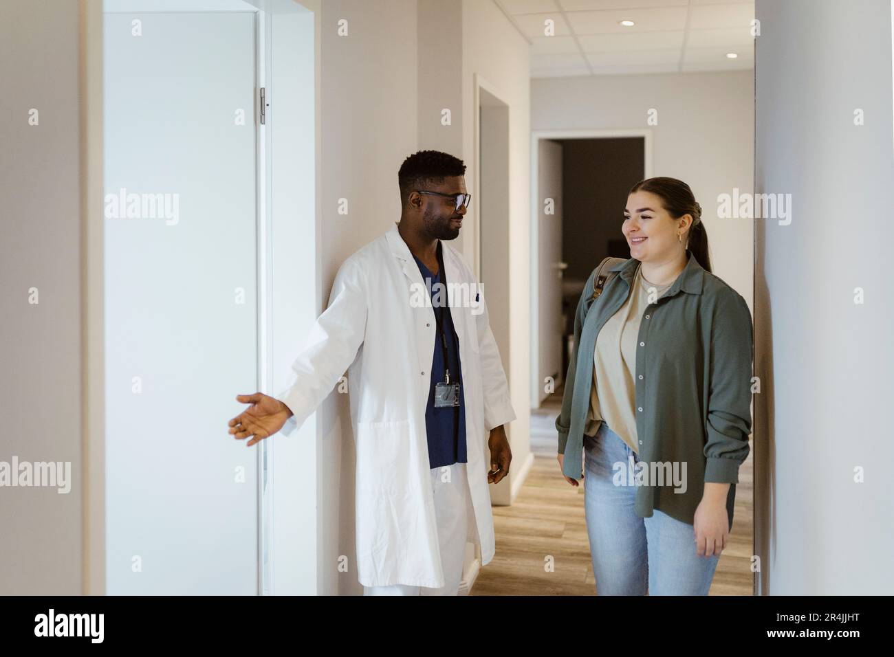 Männliche Krankenschwester, die eine Patientin beim Betreten des Sprechzimmers im Krankenhaus unterstützt Stockfoto