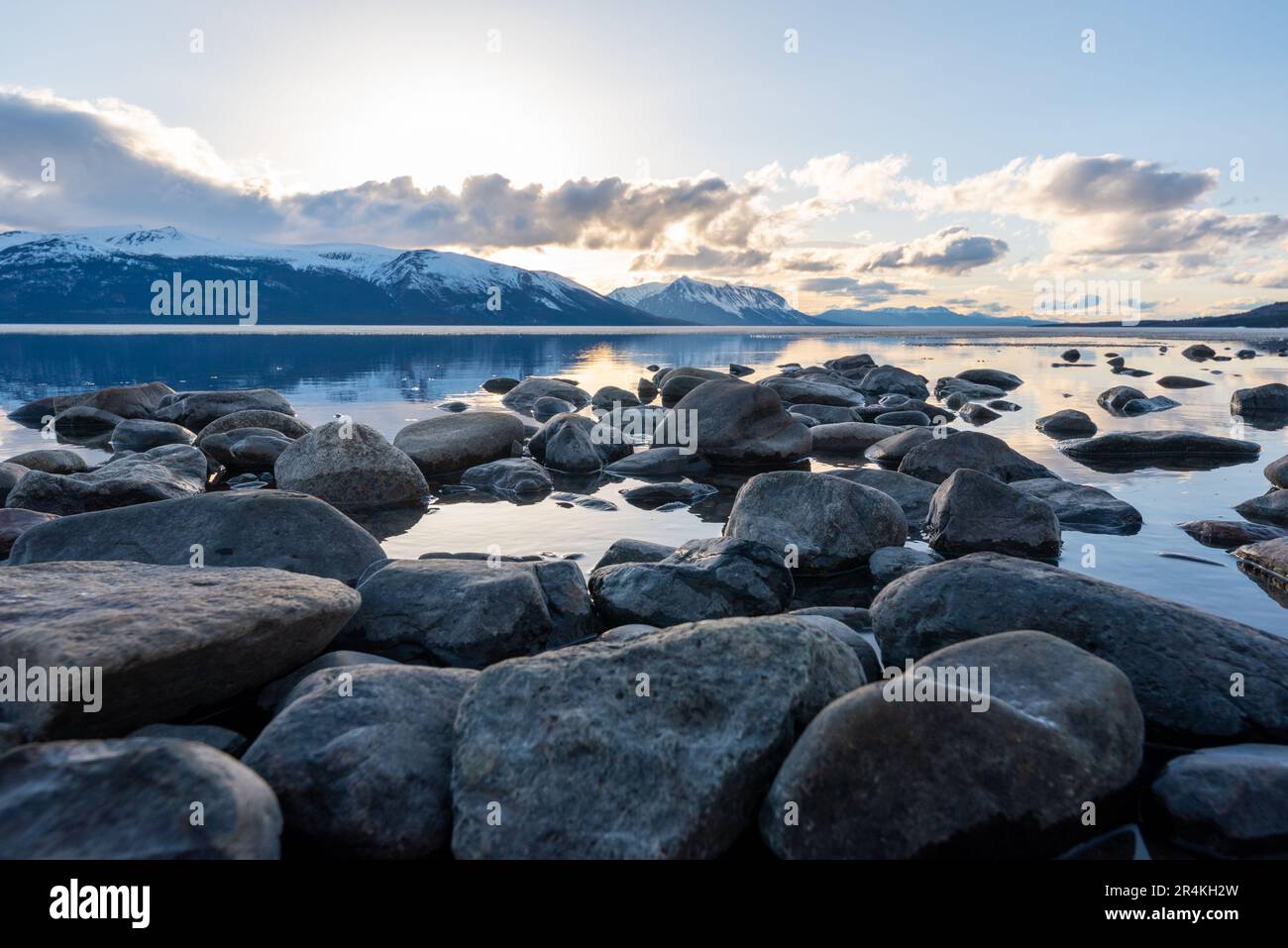 Atemberaubender See im Frühling in British Columbia mit Seeblick. Eis in der Ferne, Felsen und Wolken, blauer Himmel Reflexion in unberührtem Wasser. Stockfoto