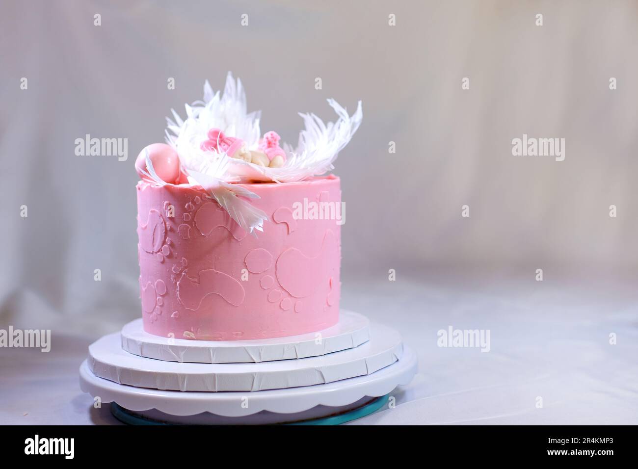 Dekoration eines Kuchens für eine Familie Taufe rosa Kuchen mit Fußabdrücken eines kleinen Kindes auf Engelsflügeln und Baby in rosa Windel ein Mädchen, wie man das Geschlecht des Kindes mithilfe eines Kuchens herausfinden kann Stockfoto