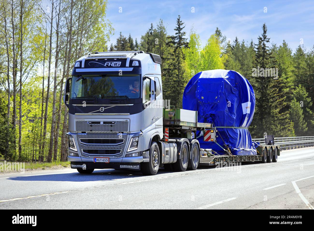 Silberner Volvo FH16 650-Lkw transportiert mit Plane verkleidete industrielle Objekte auf einem Anhänger als große Last auf der Autobahn 2. Jokioinen, Finnland. 19. Mai 2023 Stockfoto