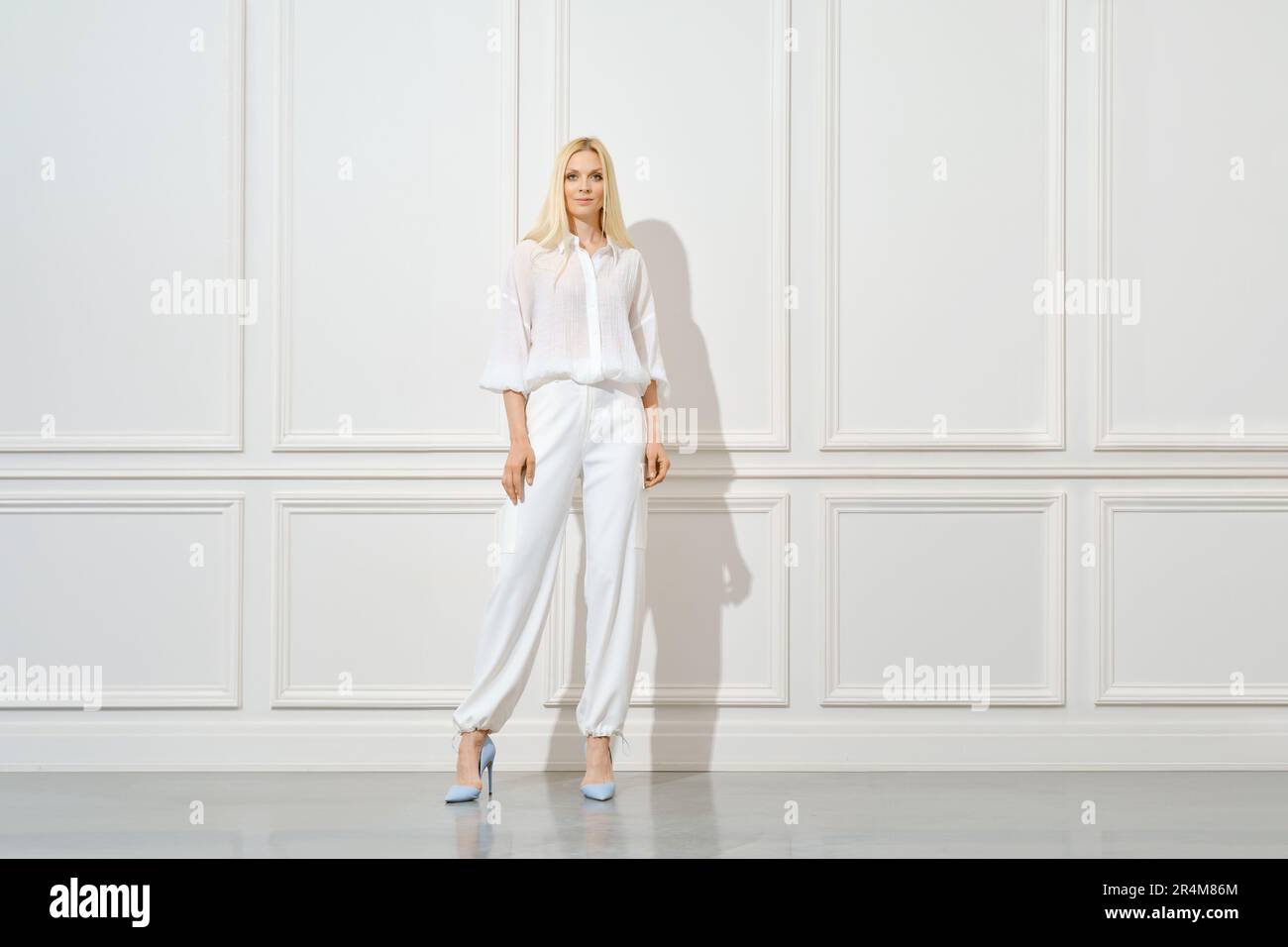 Selbstbewusste blonde Frau in totalem weißen Outfit Stockfoto