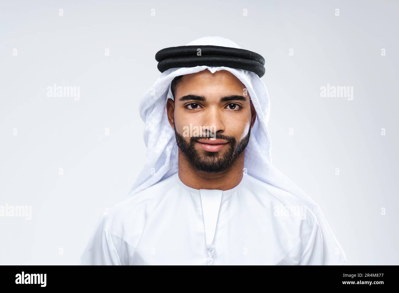 Attraktiver arabischer Mann aus dem Nahen Osten mit traditioneller Kandora im Studio - arabisch-muslimisches männliches Porträt mit emiratem Gewand in Dubai, Vereinigte Arabische Stockfoto