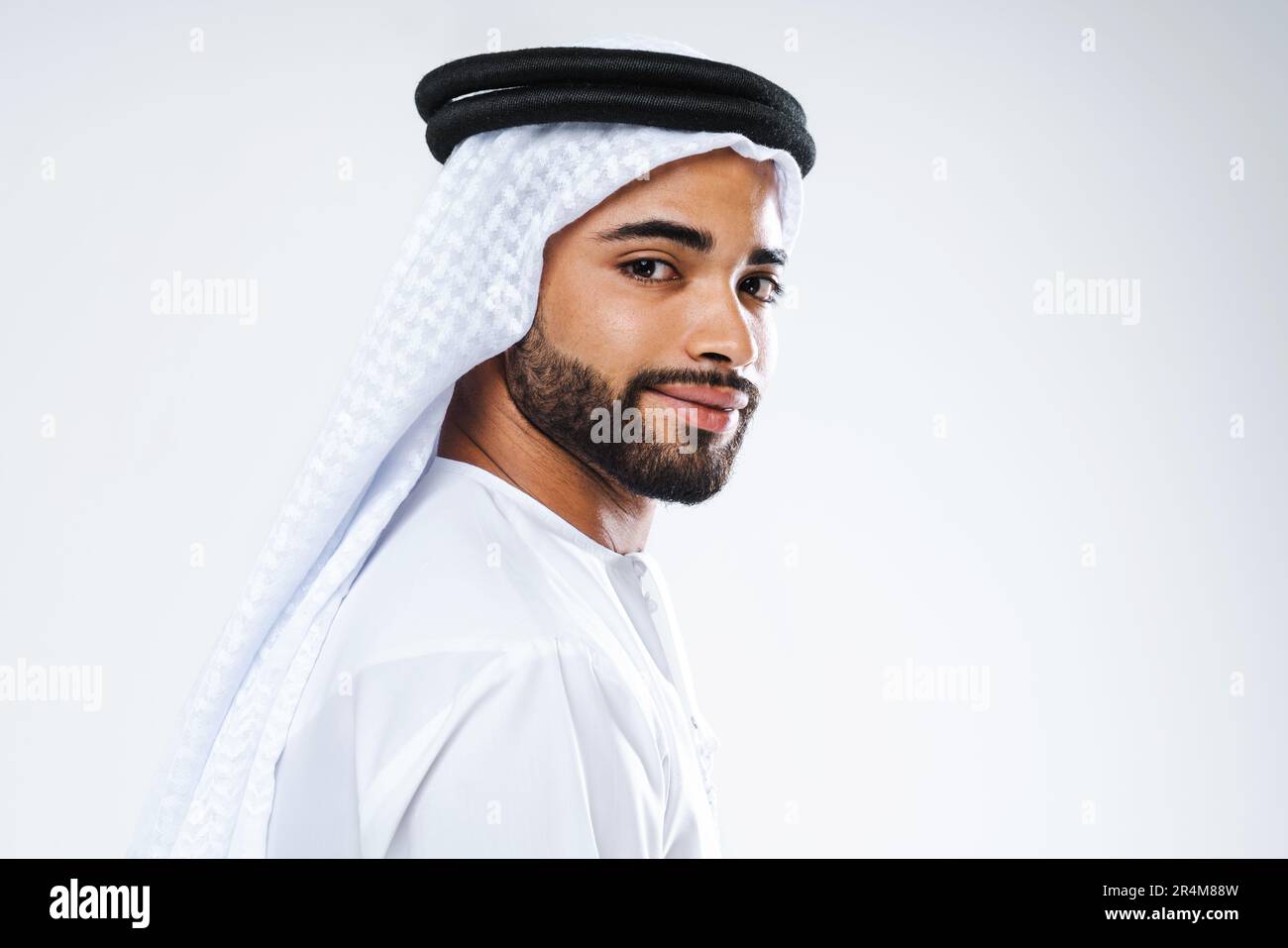 Attraktiver arabischer Mann aus dem Nahen Osten mit traditioneller Kandora im Studio - arabisch-muslimisches männliches Porträt mit emiratem Gewand in Dubai, Vereinigte Arabische Stockfoto